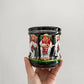 Hand holding a decorative jar with painted figures on a plain background